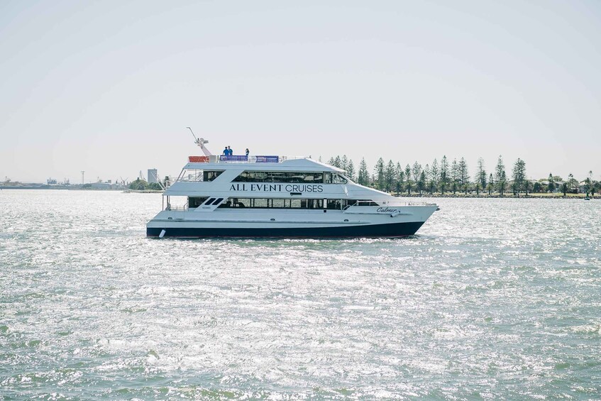 A large white cruise ship with 'ALL EVENT CRUISES' written on its side, sailing on a body of water with a forested shoreline in the background. 2