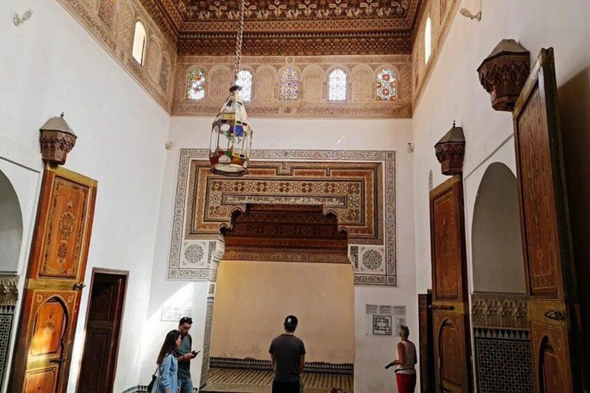 An interior with ornate wooden doors, a hanging lantern, and patterned wall designs. 4