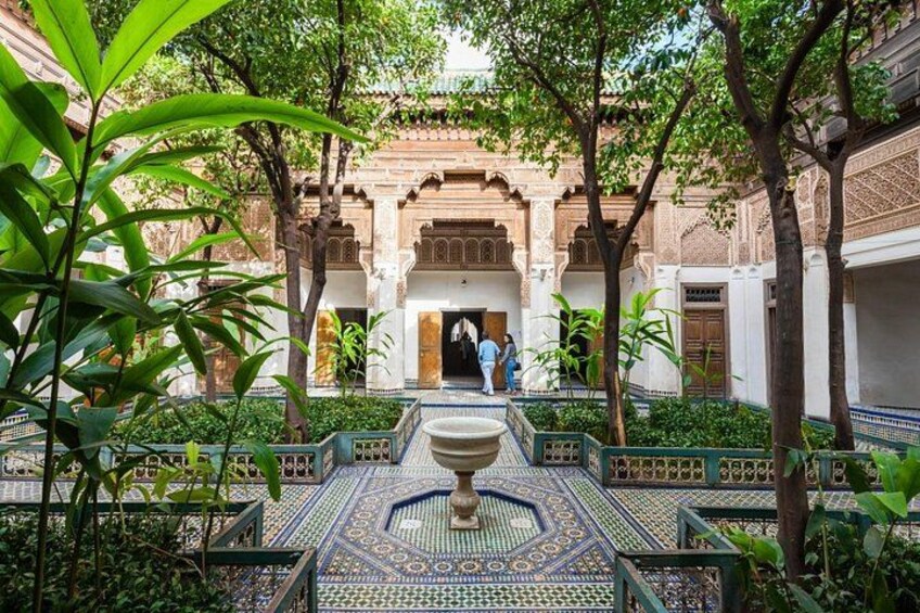 A courtyard with a fountain, tiled floor, and arches. 1
