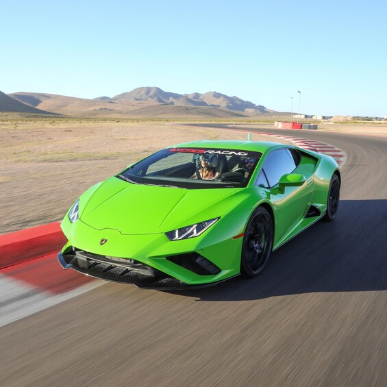 A bright green sports car on a race track with mountains in the background. 2