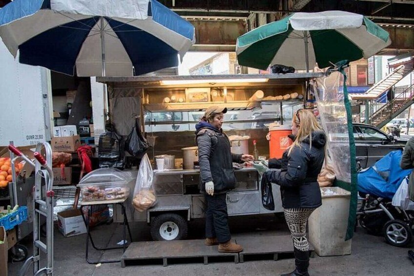 A street food vendor with a food stall, a customer, and a blue and white umbrella. 5
