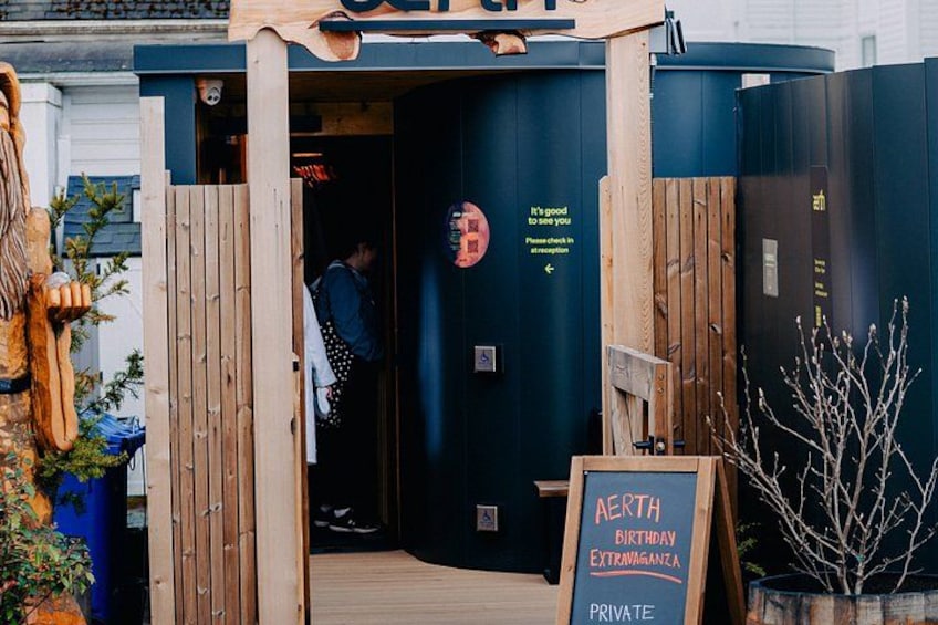 A wooden entrance to a private establishment with a signboard reading 'AERTH BIRTHDAY EXTRAORDINARY' and a person entering. 3