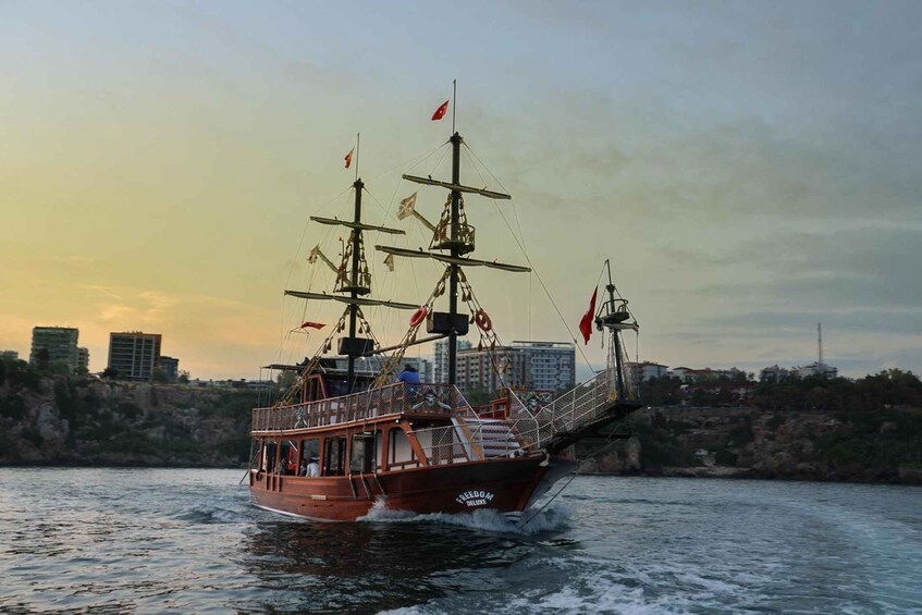 A tall ship named 'Freedom' sailing on water with a city skyline in the background. 2