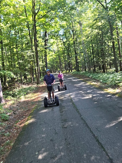Two people riding segways on a tree-lined road. 4