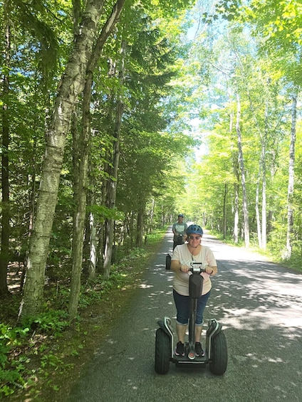A person riding a Segway on a tree-lined path. 5