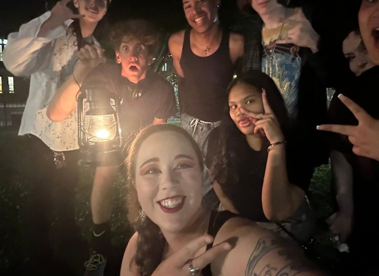 A group of people outdoors at night, some holding a lantern. 5