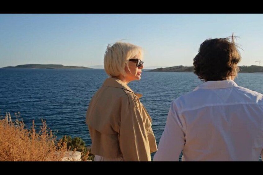 Two people standing by a body of water with a distant landmass. 5