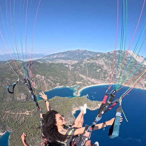A person paragliding over a coastal landscape with a mountainous backdrop. 3