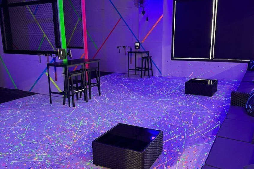 A room with a floor covered in colorful lines, a table with chairs, and a projector on the floor. 4