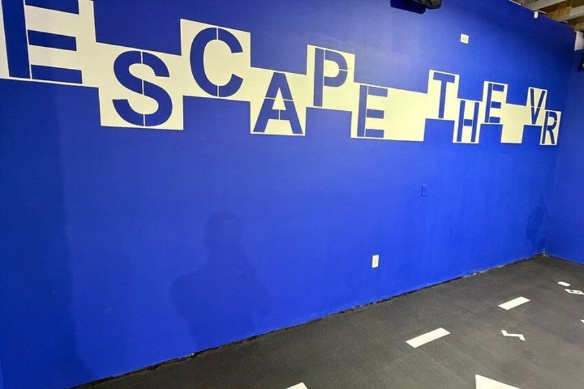 A blue wall with large white letters spelling 'ESCAPE THE VR.' 3