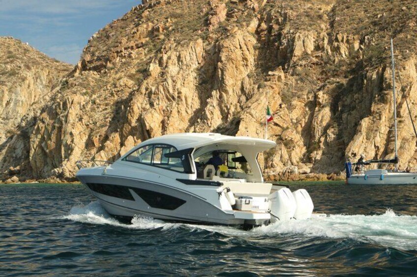 A speedboat on water with a rocky cliff in the background. 2