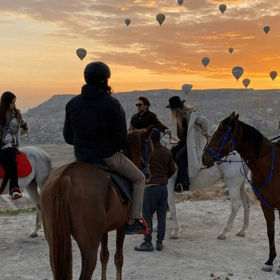 People on horseback with hot air balloons in the background. 3