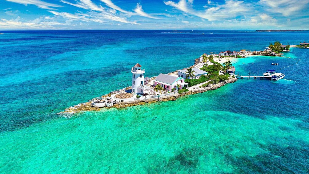 An island with a lighthouse, clear turquoise waters, and a small pier. 2