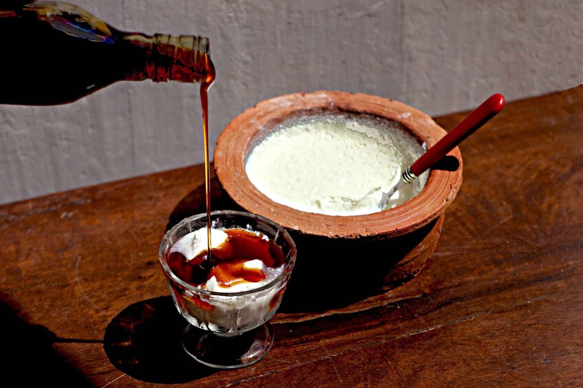 Una ciotola di gelato con un cucchiaio, un bicchiere di latte con sciroppo al cioccolato e una bottiglia che versa sciroppo. 3