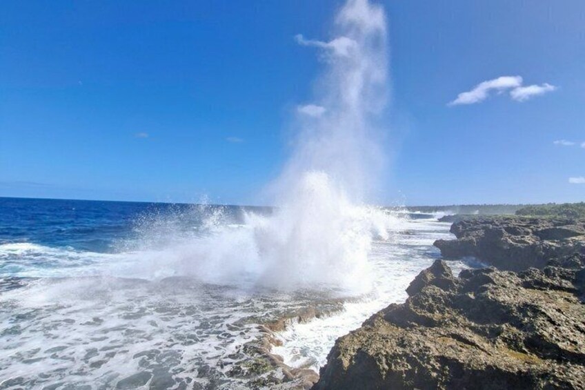 A coastal scene with waves crashing against rocky cliffs and a clear blue sky. 2