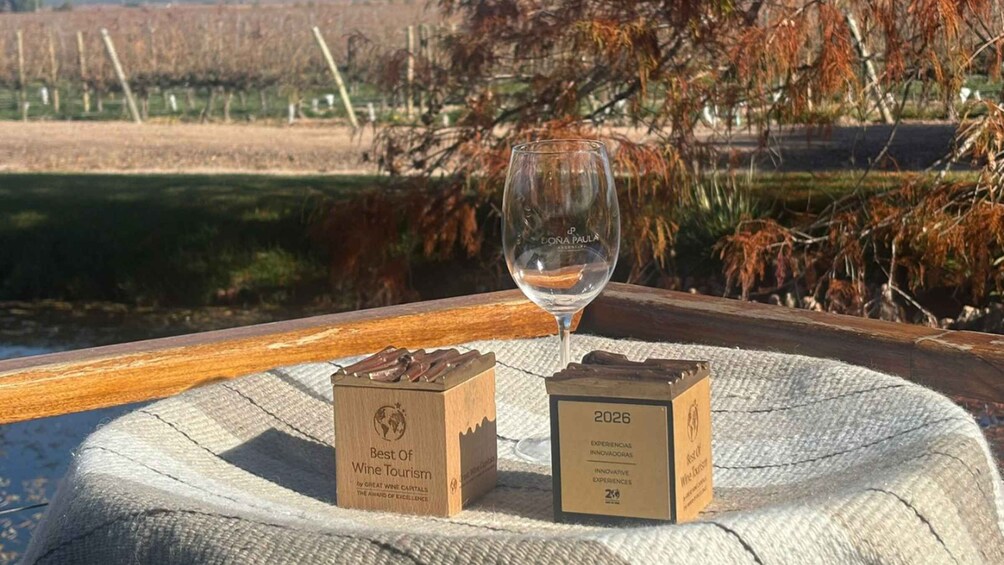 A wine glass on a wooden table with two wooden boxes labeled 'Best of Wine Tourism' and '2026.' 3