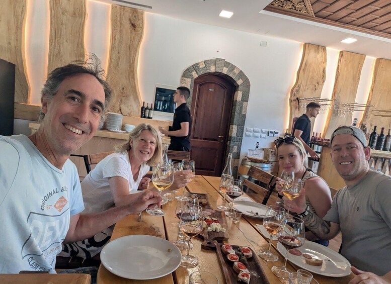 A group of people seated at a wooden table in a restaurant with wine glasses and plates of food. 5