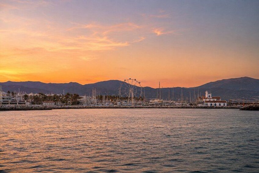 A coastal sunset with a Ferris wheel, boats, and a marina. 3
