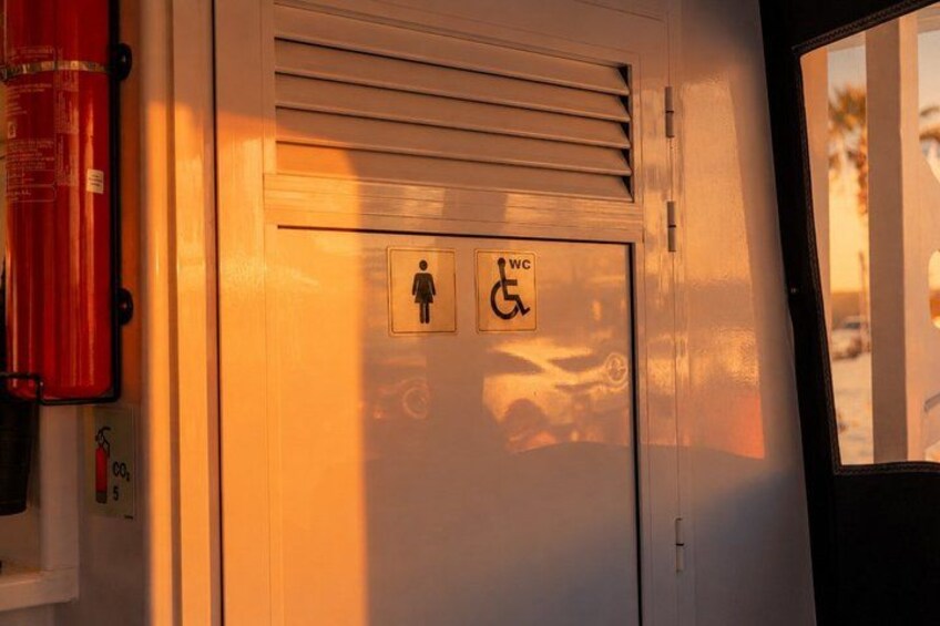 A door with a wheelchair accessibility sign, a fire extinguisher, and a window. 2