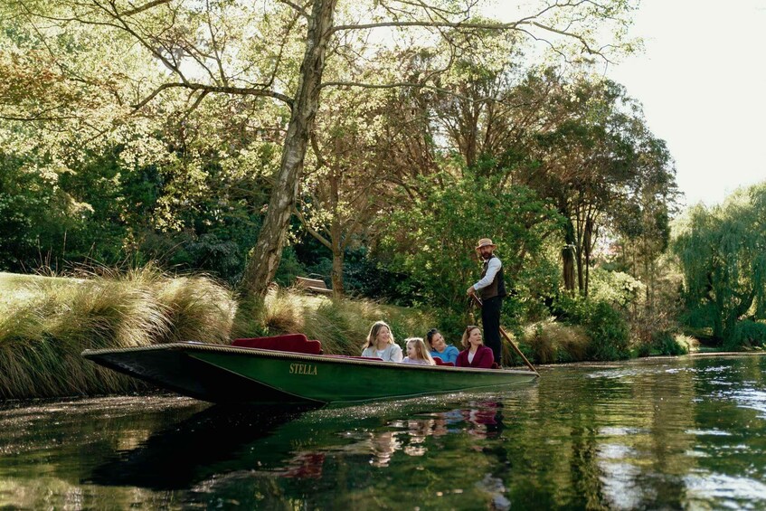 A green boat named 'STELLA' on a river surrounded by trees and grass. 3