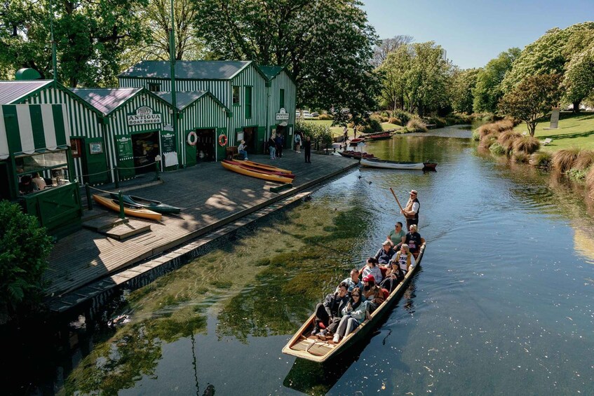 A green boat house with canoes and a rowboat on a calm river. 1
