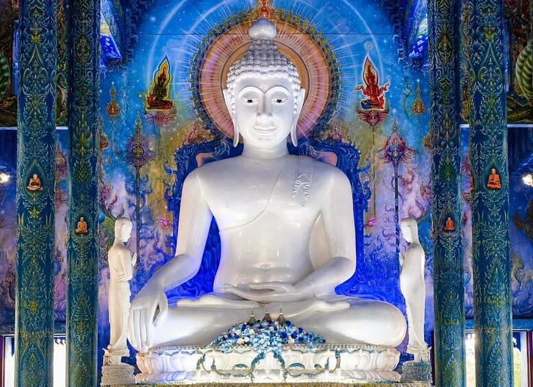 A large white Buddha statue in a meditative pose, surrounded by ornate columns and colorful murals. 3
