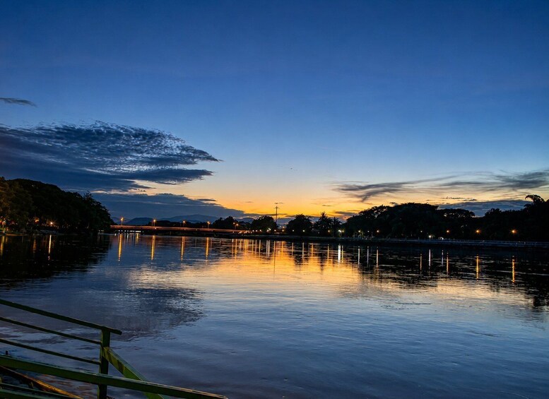 A calm lake at dusk with a bridge in the distance and city lights reflecting on the water. 5