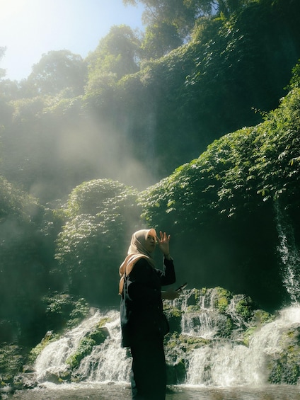 A person standing by a waterfall in a forested area. 2