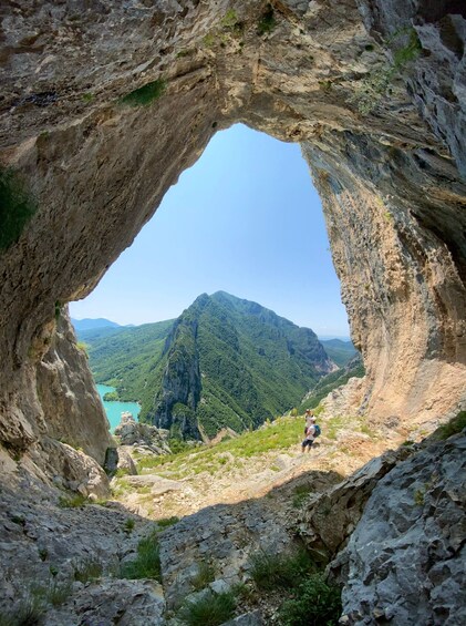 A natural rock arch framing a mountainous landscape with a clear sky. 4