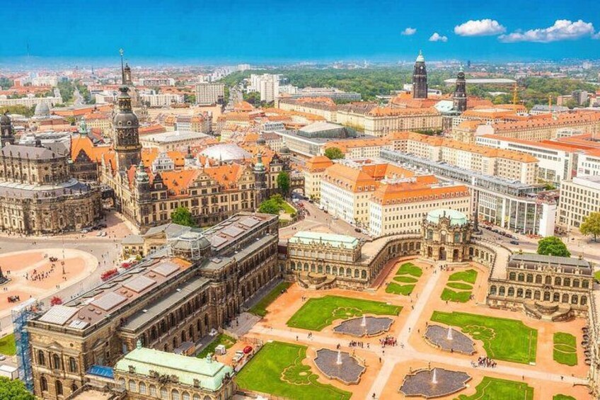 An aerial view of a historic city center with prominent buildings, a large square, and a river. 1