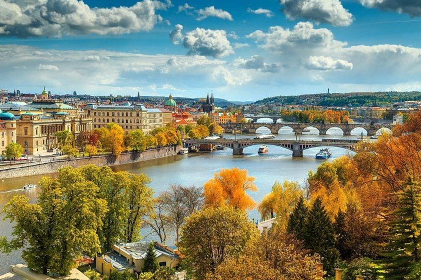 A river with a bridge, autumn trees, and historic buildings. 1