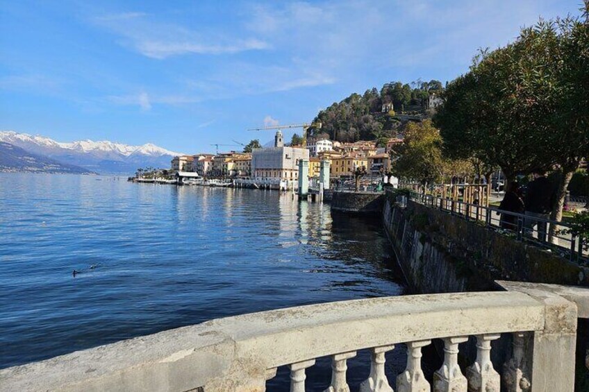 A calm lake with a stone bridge, buildings, and snow-capped mountains in the background. 2