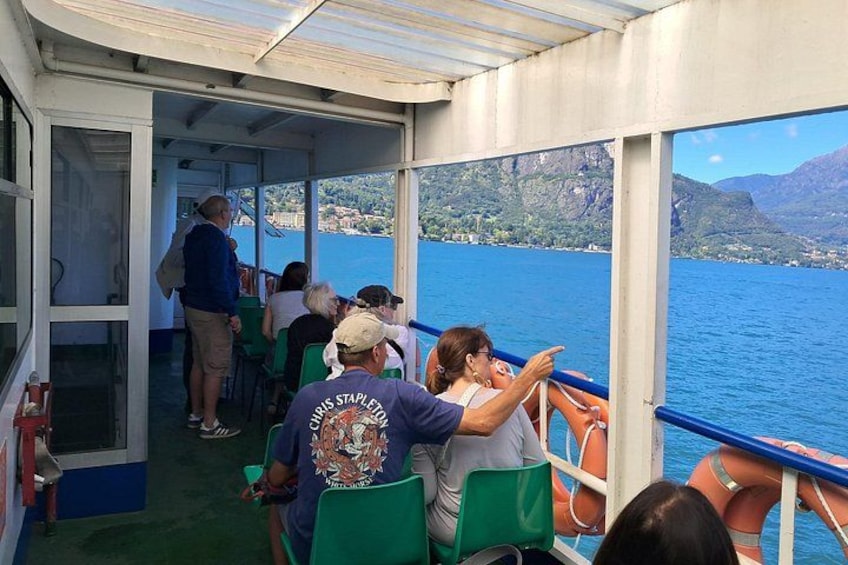 A boat with people seated, looking out at a body of water with mountains in the background. 2