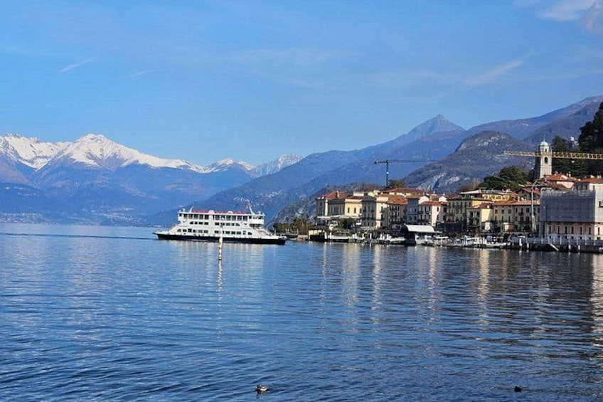 A lake with a boat, buildings, and mountains in the background. 3