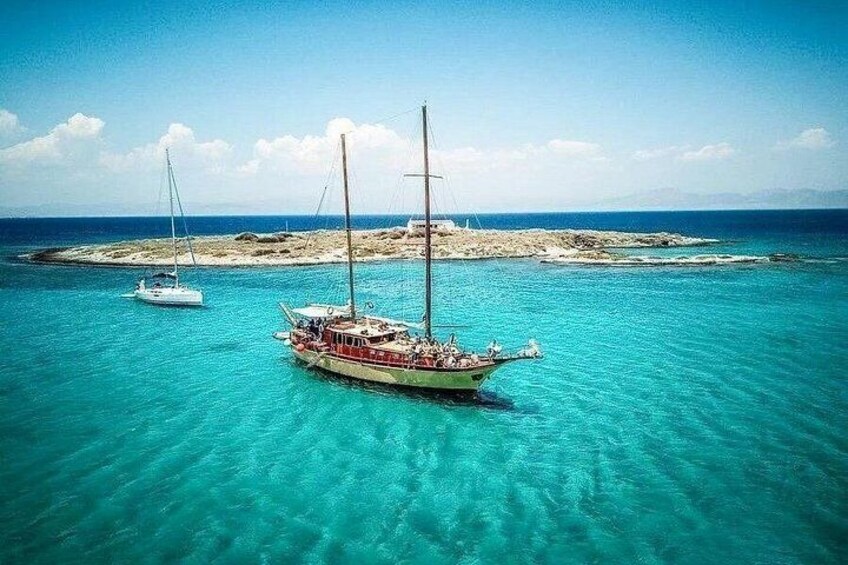 A boat anchored in turquoise waters with a rocky island in the background. 5