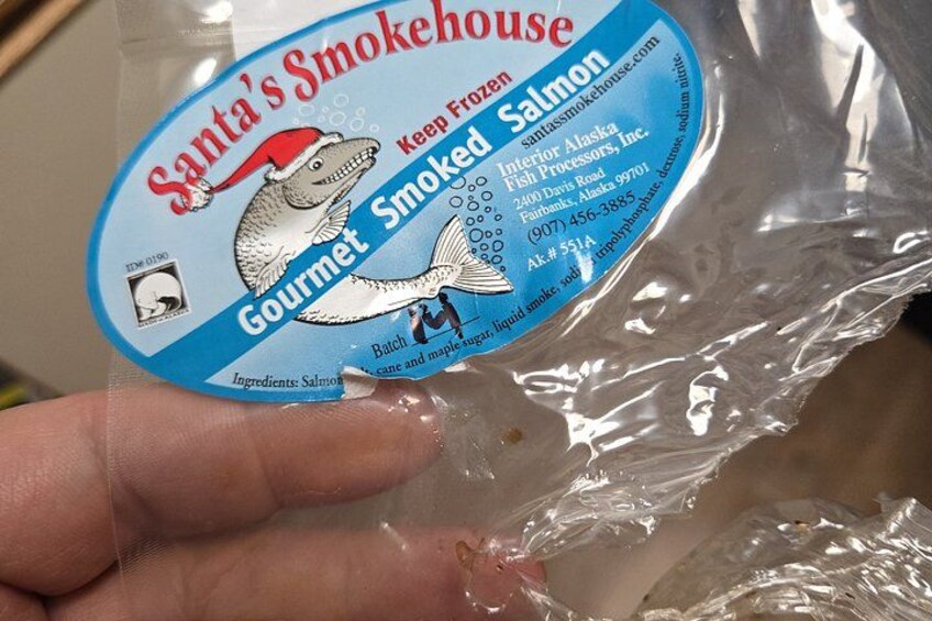 A hand holding a package labeled 'Santa's Smokehouse Gourmet Smoked Salmon.' 4