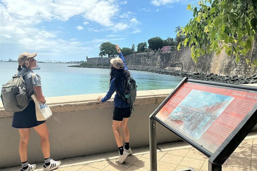 Two people standing by a waterfront with a historical marker. 5
