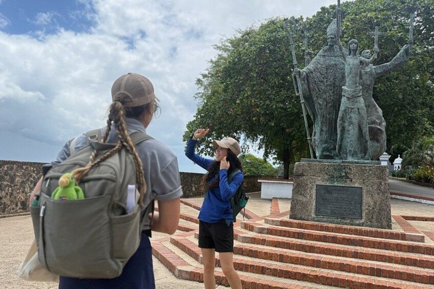 A person taking a photo of a statue with a backpack and a water bottle. 3