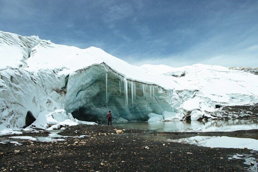 A glacier with a person standing in front of a crevasse. 5
