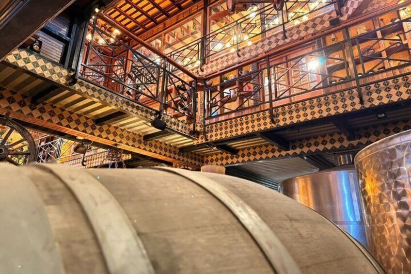A brewery interior with large stainless steel tanks and a decorative metal staircase. 3