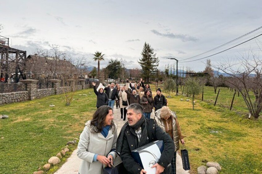 A group of people walking on a path in a park with trees and a stone structure in the background. 2