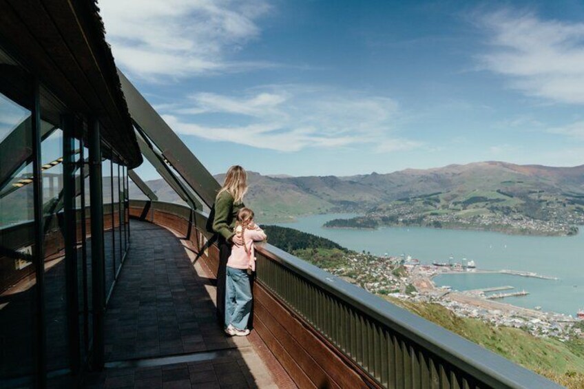 A woman and child on a glass bridge overlooking a lake and mountains. 2