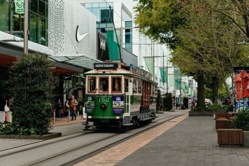 A green trolley labeled 'City Tour' on a street with modern buildings and trees. 5