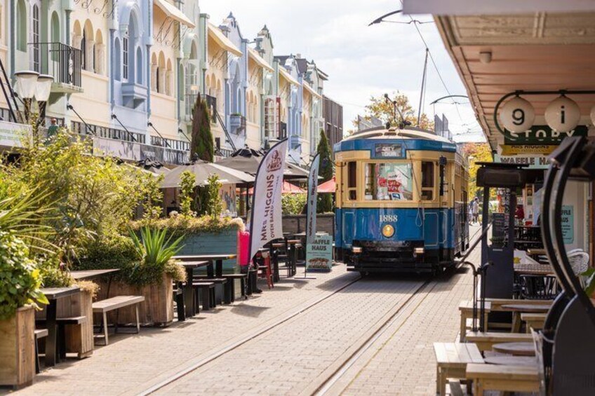 A tram on tracks, outdoor seating, and buildings with signage. 4