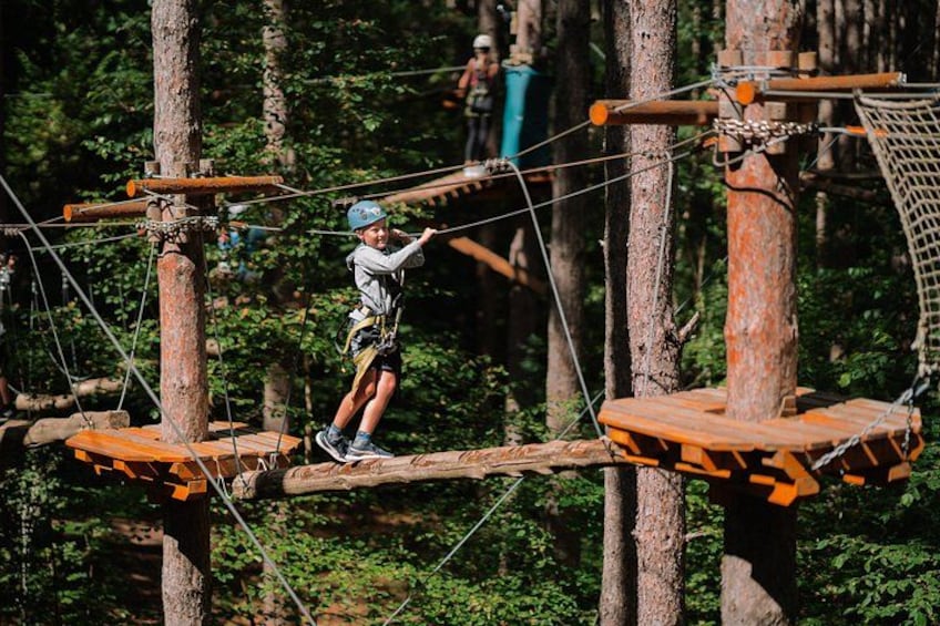 A person navigating a rope bridge in a forested area. 5