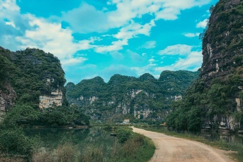 A dirt road winding through a valley with dense greenery and rocky cliffs. 3
