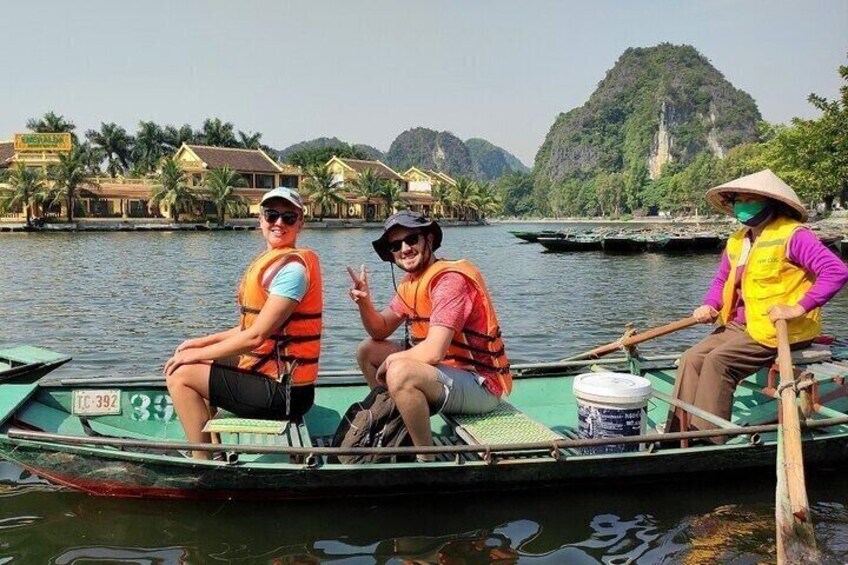 Three people on a boat with a water body and buildings in the background. 2