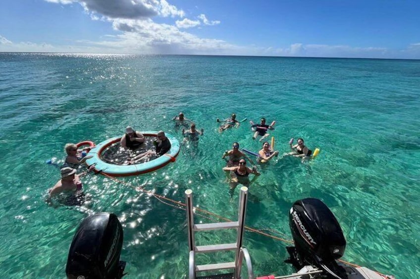 People floating on a clear blue sea, a floating platform, and a boat's outboard motor. 3
