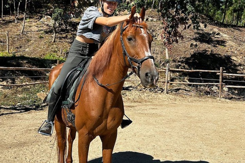 A person riding a horse in an outdoor setting with a dirt ground and a wooden fence in the background. 2
