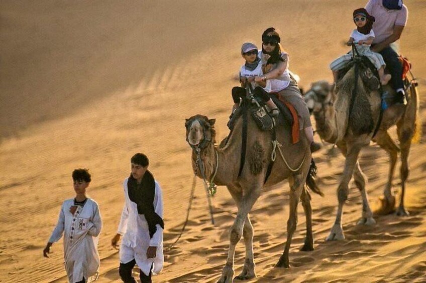 A camel caravan in a desert with people riding camels. 2